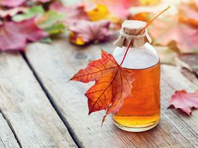 Maple syrup in jar on table with colorful maple leaves